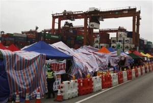 A policeman walks past tents set up by protesting dock workers outside Kwai Chung container terminal in Hong Kong